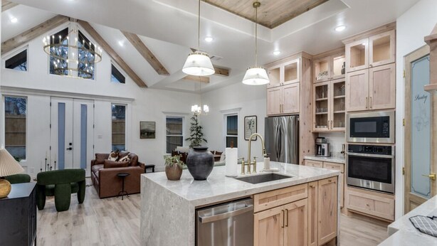 A spacious kitchen with wooden cabinets, a large island with a sink, and modern appliances. - New! 4 BDRM Home near stockyards & DT Fort Worth (Fort Worth)