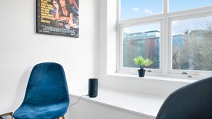 A room with a large window, a blue chair, a small potted plant, and a poster on the wall. - Spacious NG1 City Centre Apartment Near Motorpoint Arena, sleeps 6 (Nottingham)