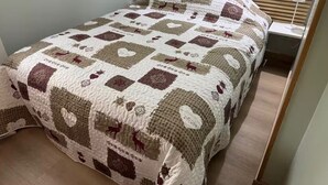 A neatly made bed with a quilt featuring a geometric pattern and animal motifs. - Wonderful modern Chalet with private garden only 5 minutes walk to Annecy Lake. (Doussard)