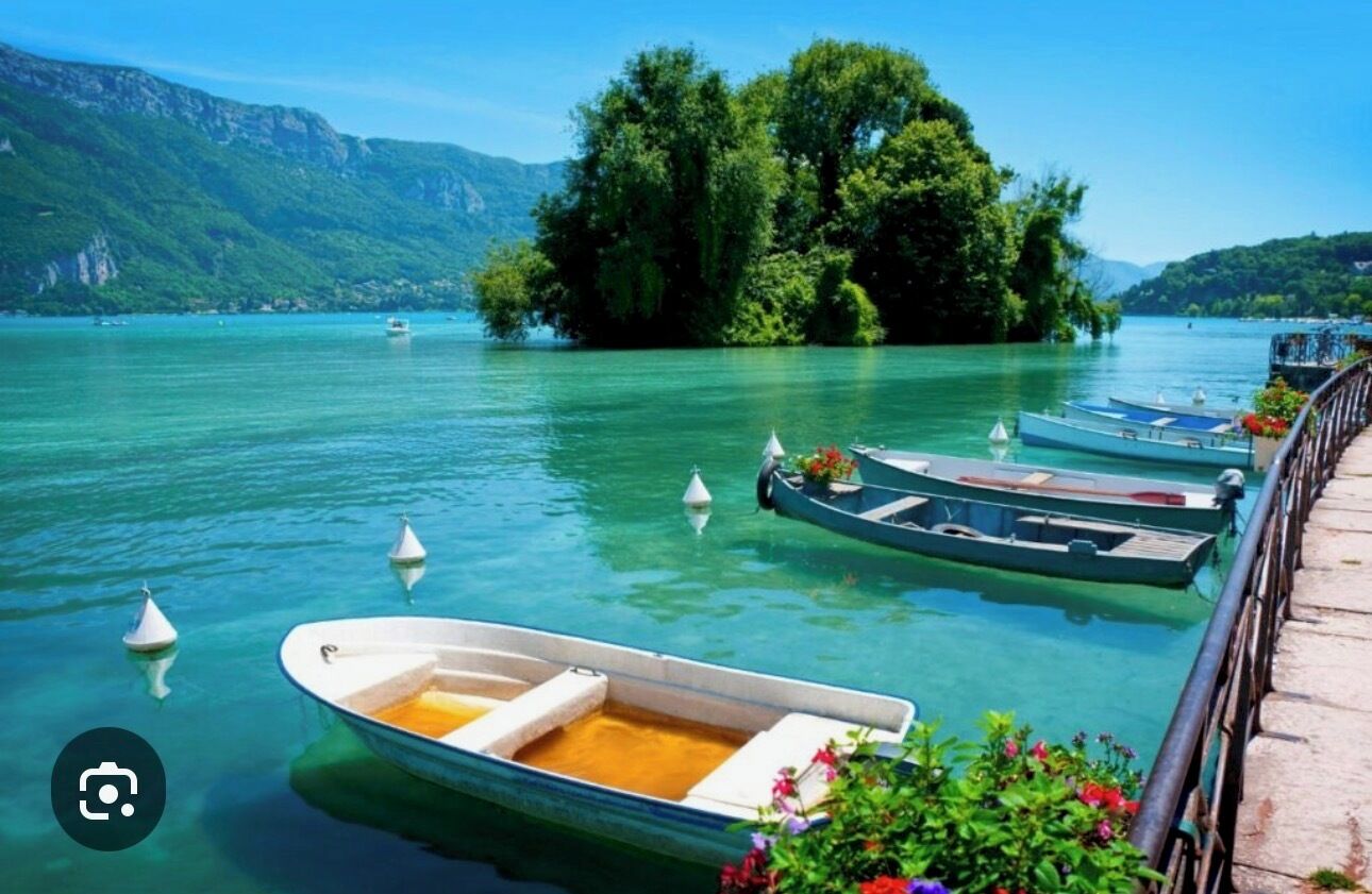 A row of boats docked at a pier with a mountainous backdrop.