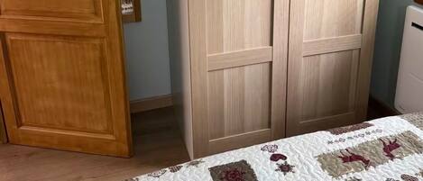 Ein Schlafzimmer mit einem Holzschrank, einem Bett mit Steppdecke und einem weißen Nachttisch.