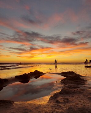 A beach scene with people walking, a sunset, and calm water reflecting the sky. - Apartment 'Jacaranda Playa Conil' with Private Terrace, Wi-Fi and Air Conditioning (Conil de la Frontera)