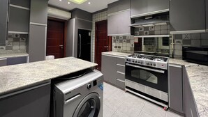 A modern kitchen with built-in appliances, a washing machine, and a microwave. - Luxury 5-Bedroom Hotel Villa – Palm Valley Compound, Sheikh Zayed, Egypt (El Sheikh Zayed City)