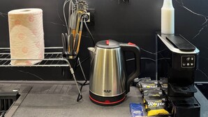 Eine Küchenarbeitsplatte mit Kaffeemaschine, Wasserkocher, Papierhandtuchhalter und Kaffee-Pad-Spender.
