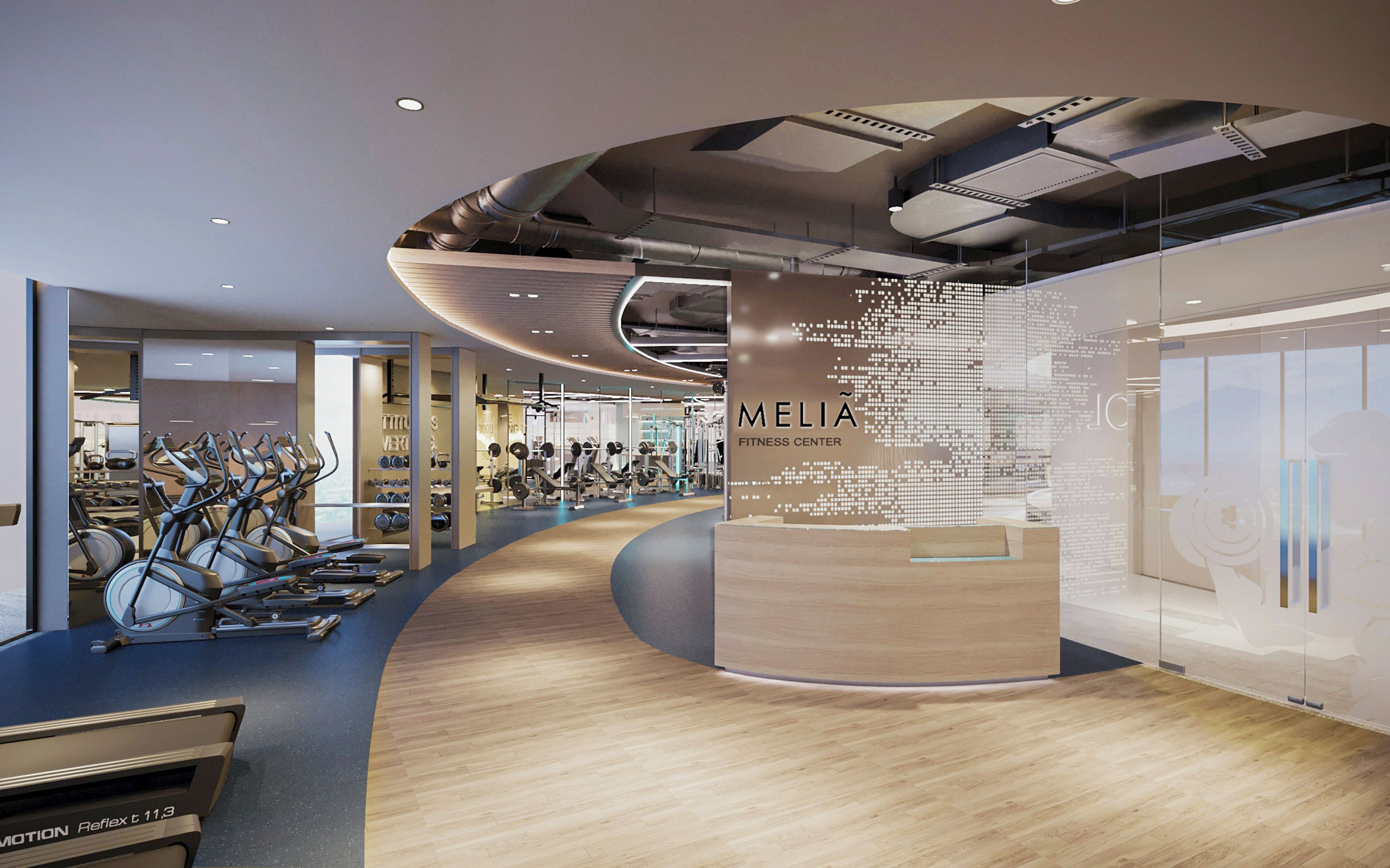Un gimnasio moderno con equipo cardiovascular, máquinas de pesas y un mostrador de información central.