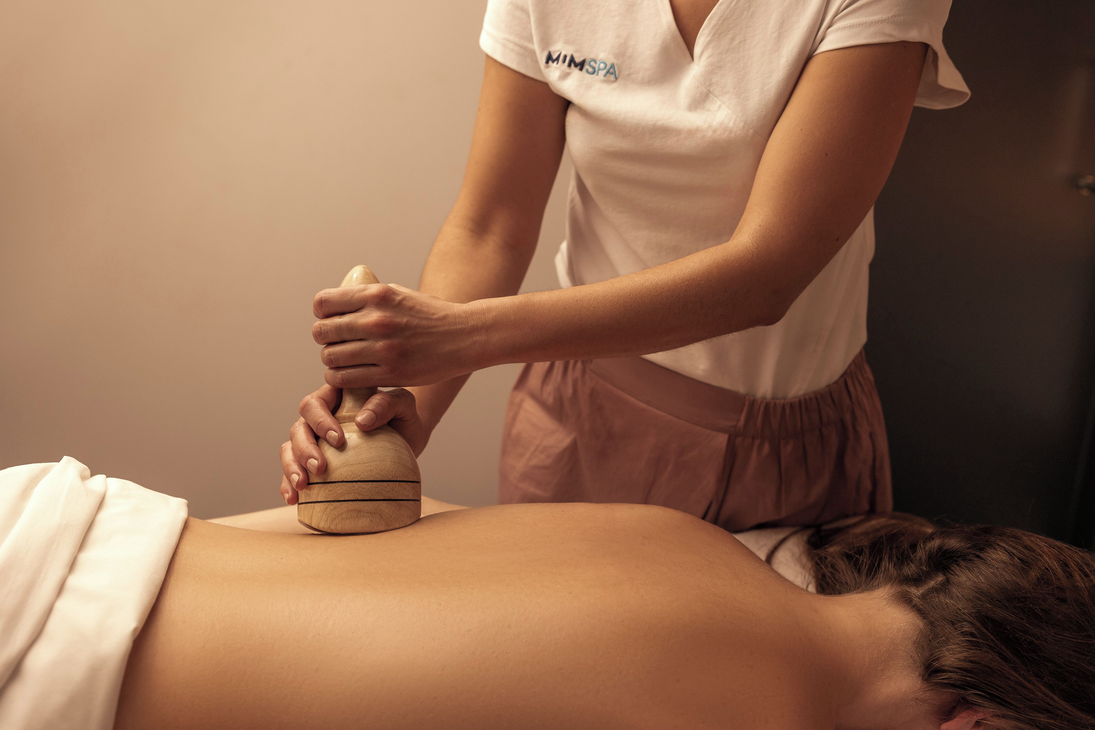 A massage therapy session with a wooden tool on a person's back.