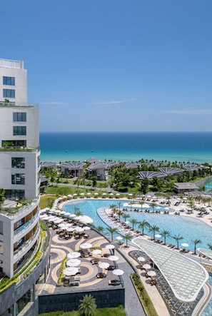 A resort with a large pool, multiple sun umbrellas, and a view of the ocean. - Melia Serenity Cam Ranh Beach Resort (Cam Lam)
