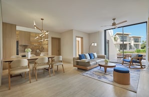 A modern living space with a dining area, sofa, and a view of a residential building. - Melia Serenity Cam Ranh Beach Resort (Cam Lam)