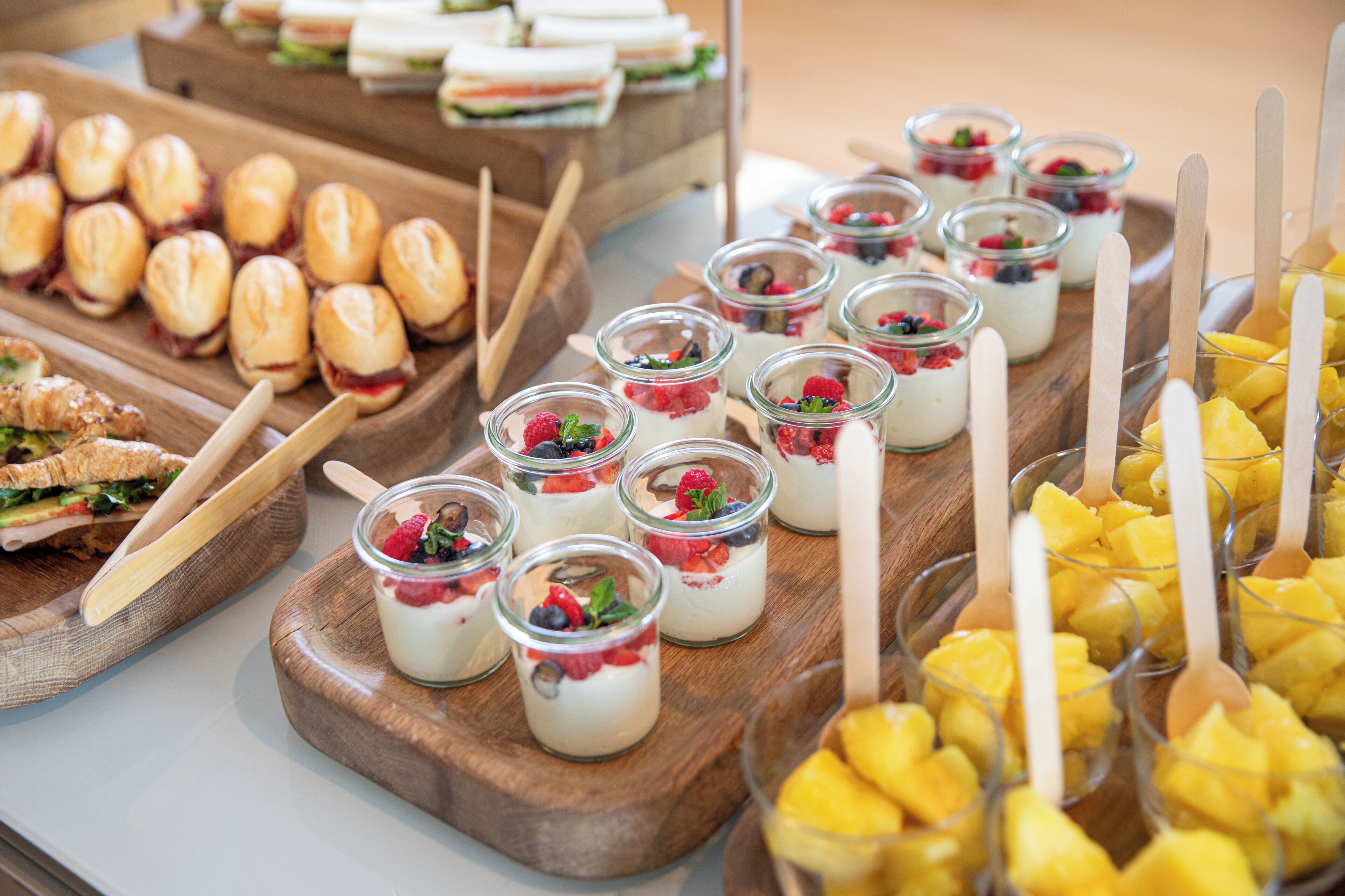 A buffet with various food items including sandwiches, fruit, and desserts.