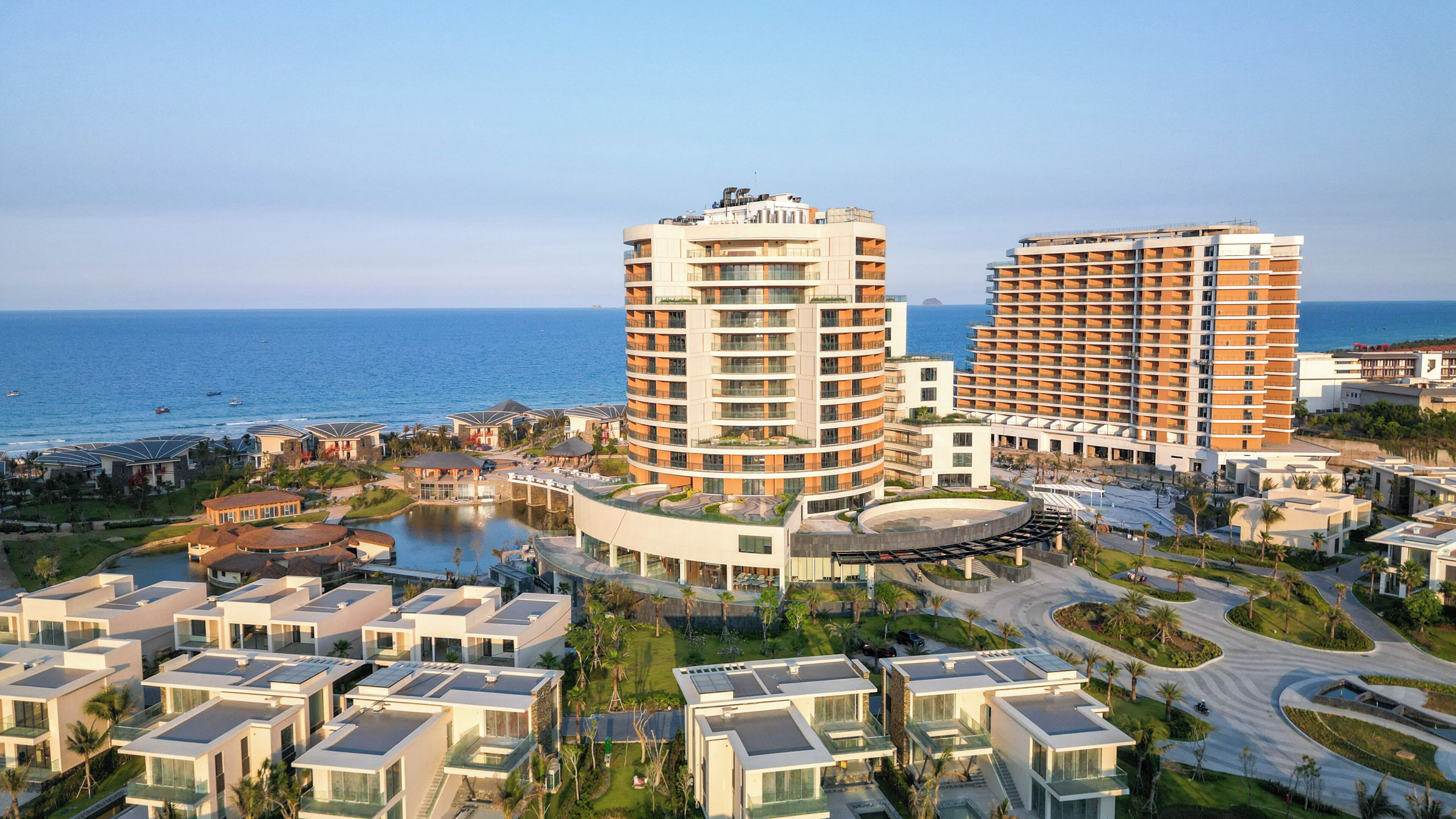 Un complejo hotelero frente al mar con varias torres, un patio central y un puerto deportivo.