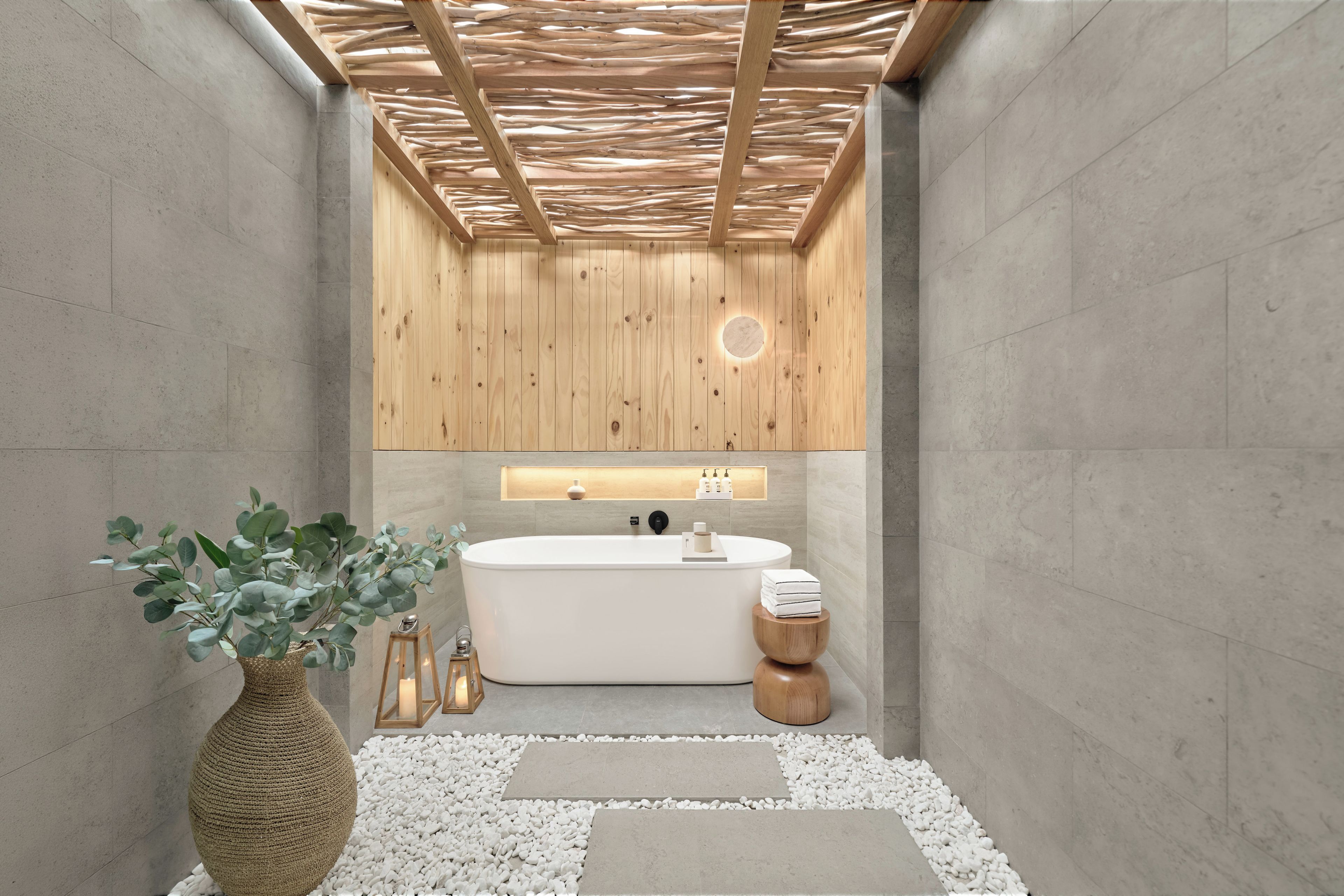 A modern bathroom with a freestanding bathtub, wooden panel walls, and a stone floor.
