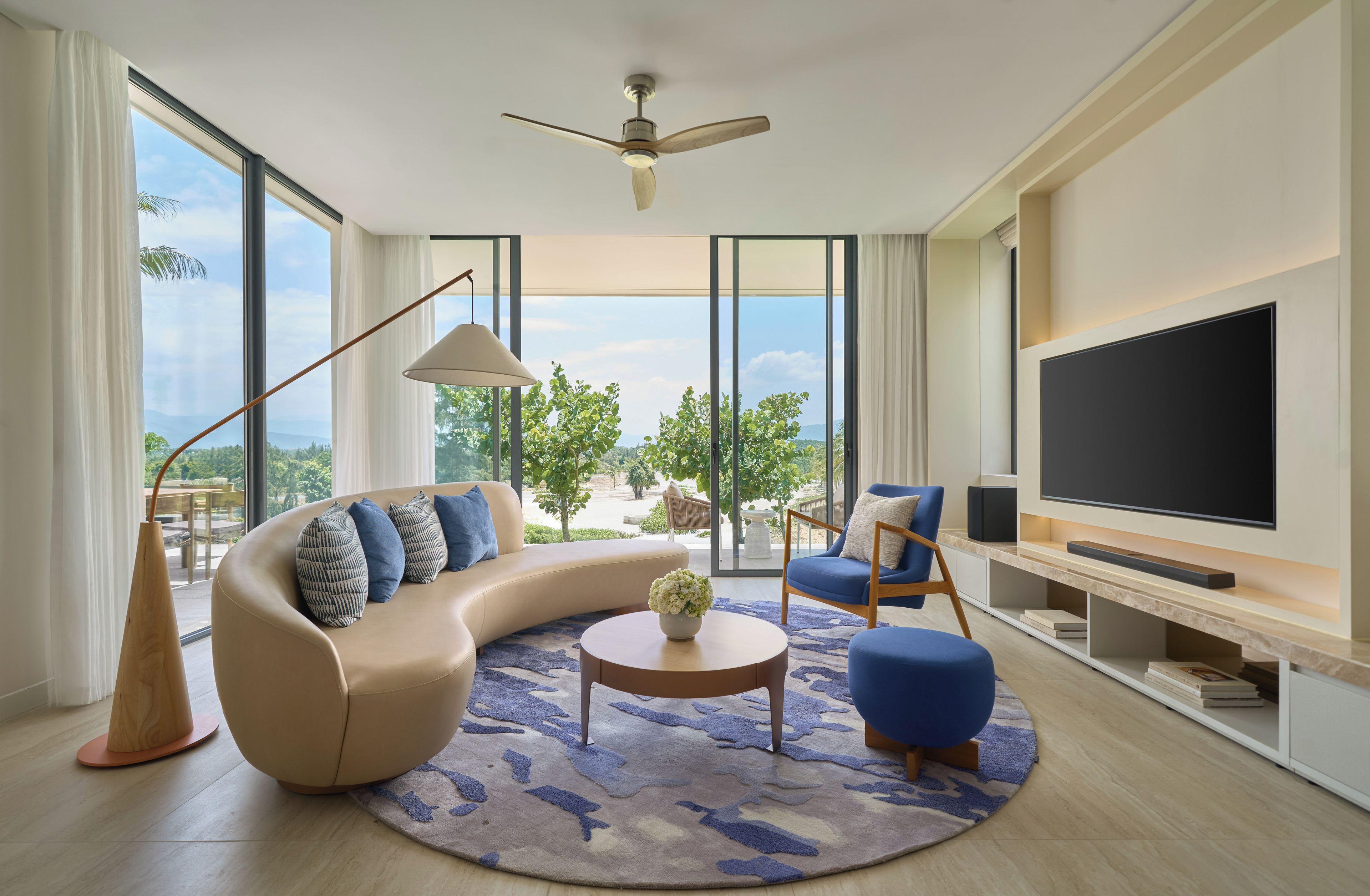 A modern living room with a curved sofa, a round coffee table, and a flat-screen TV.
