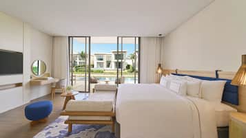 Une chambre d’hôtel moderne dotée d’un grand lit, d’une télévision, d’un bureau et offrant une vue sur une piscine et des bâtiments.