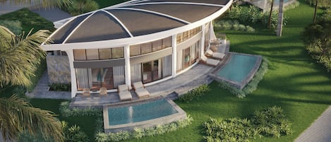 Una casa moderna con techo curvo, piscina y jardín cuidado.