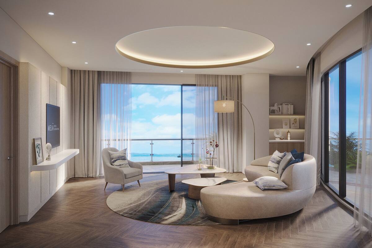 Ein modernes Wohnzimmer mit einer gebogenen Couch, einem Couchtisch und Blick auf das Meer durch große Fenster.