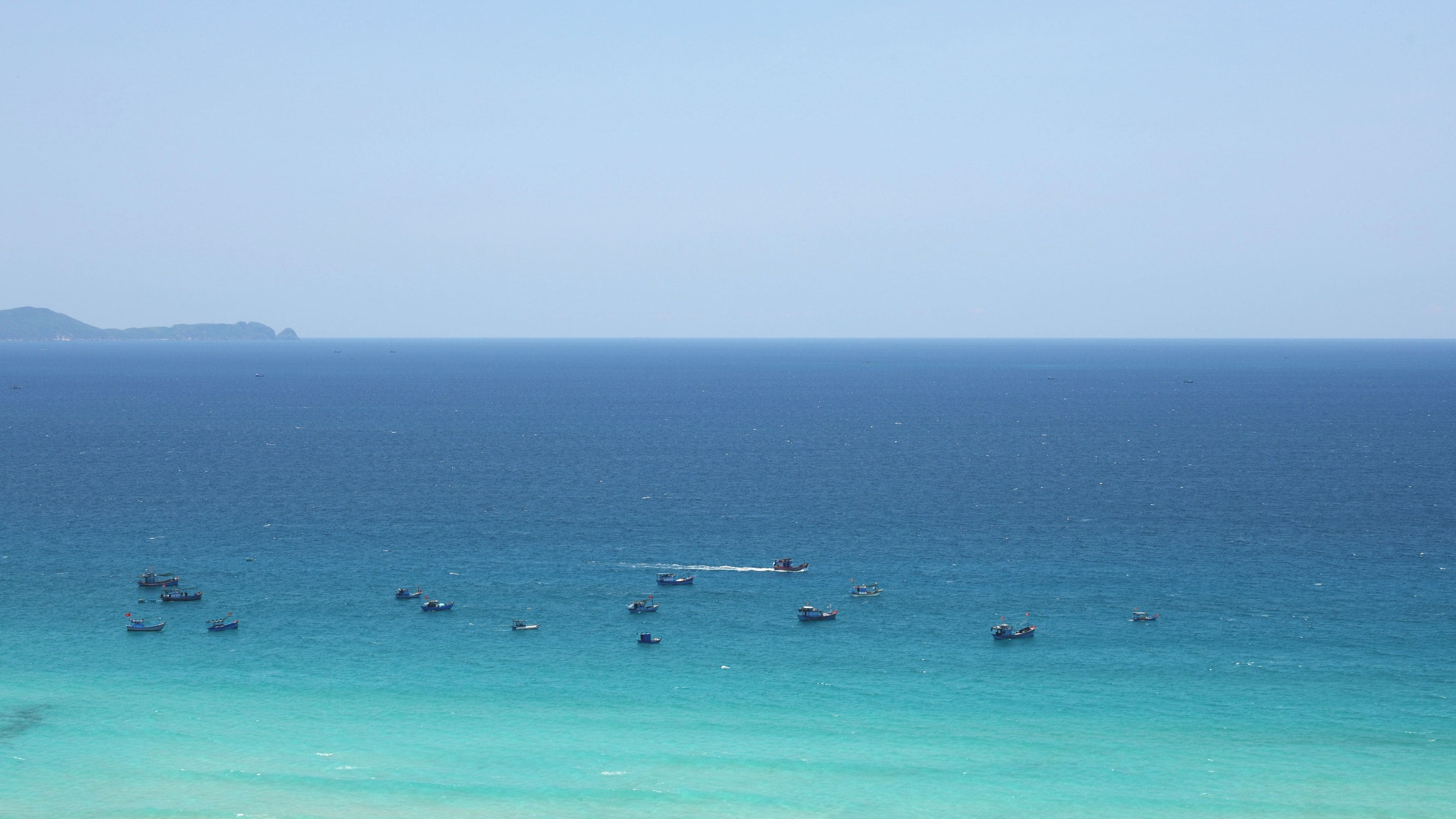 A coastal view with several boats on calm waters.