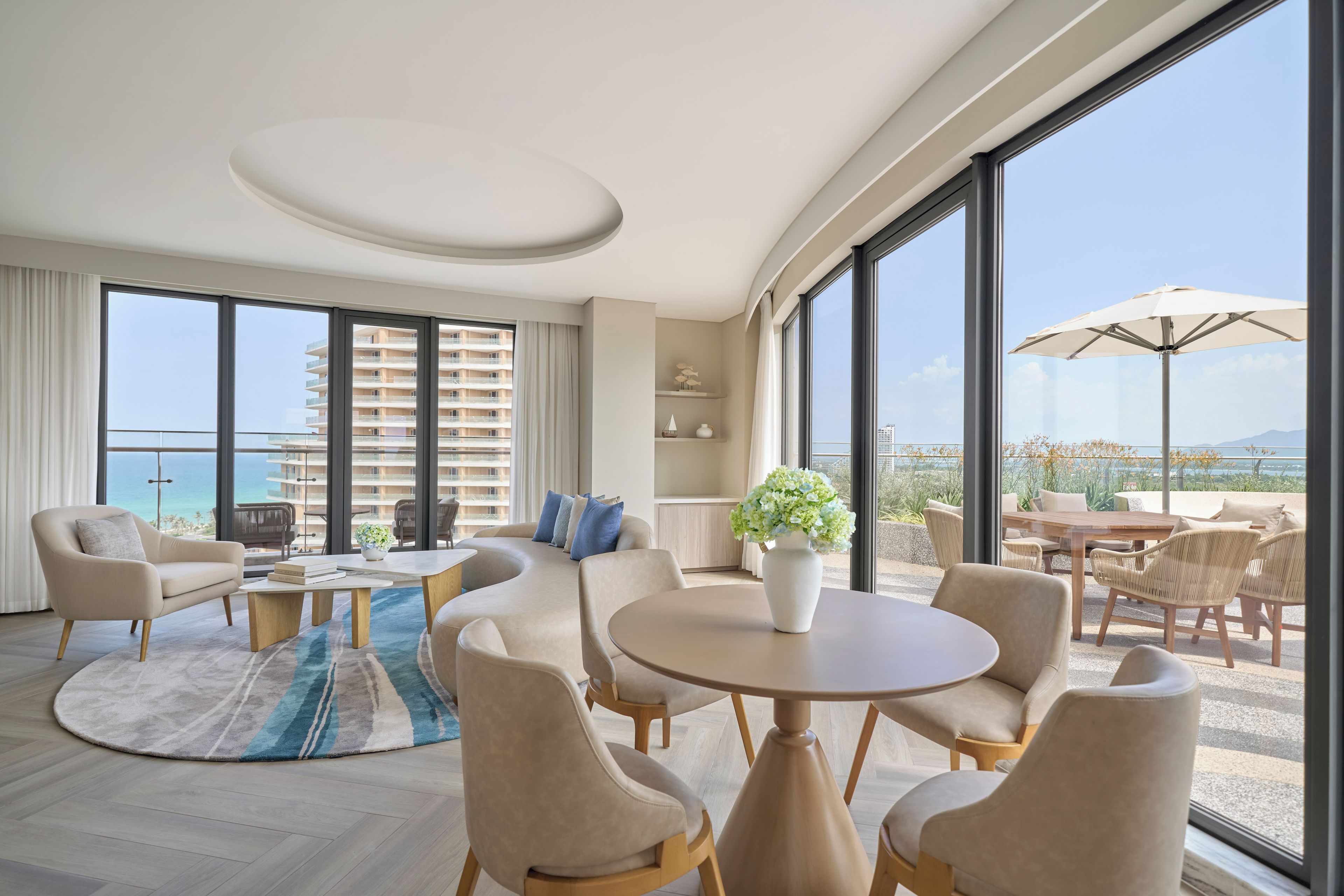 Une chambre d’hôtel moderne dotée d’un grand balcon, d’une table à manger ronde et d’un ensemble de canapés.
