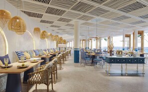 A restaurant with a long dining area, multiple tables, wicker chairs, and hanging light fixtures. - Melia Serenity Cam Ranh Beach Resort (Cam Lam)