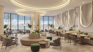 A spacious lobby with a central seating area, large windows offering a view of a pool and resort buildings, and modern lighting fixtures. - Melia Serenity Cam Ranh Beach Resort (Cam Lam)