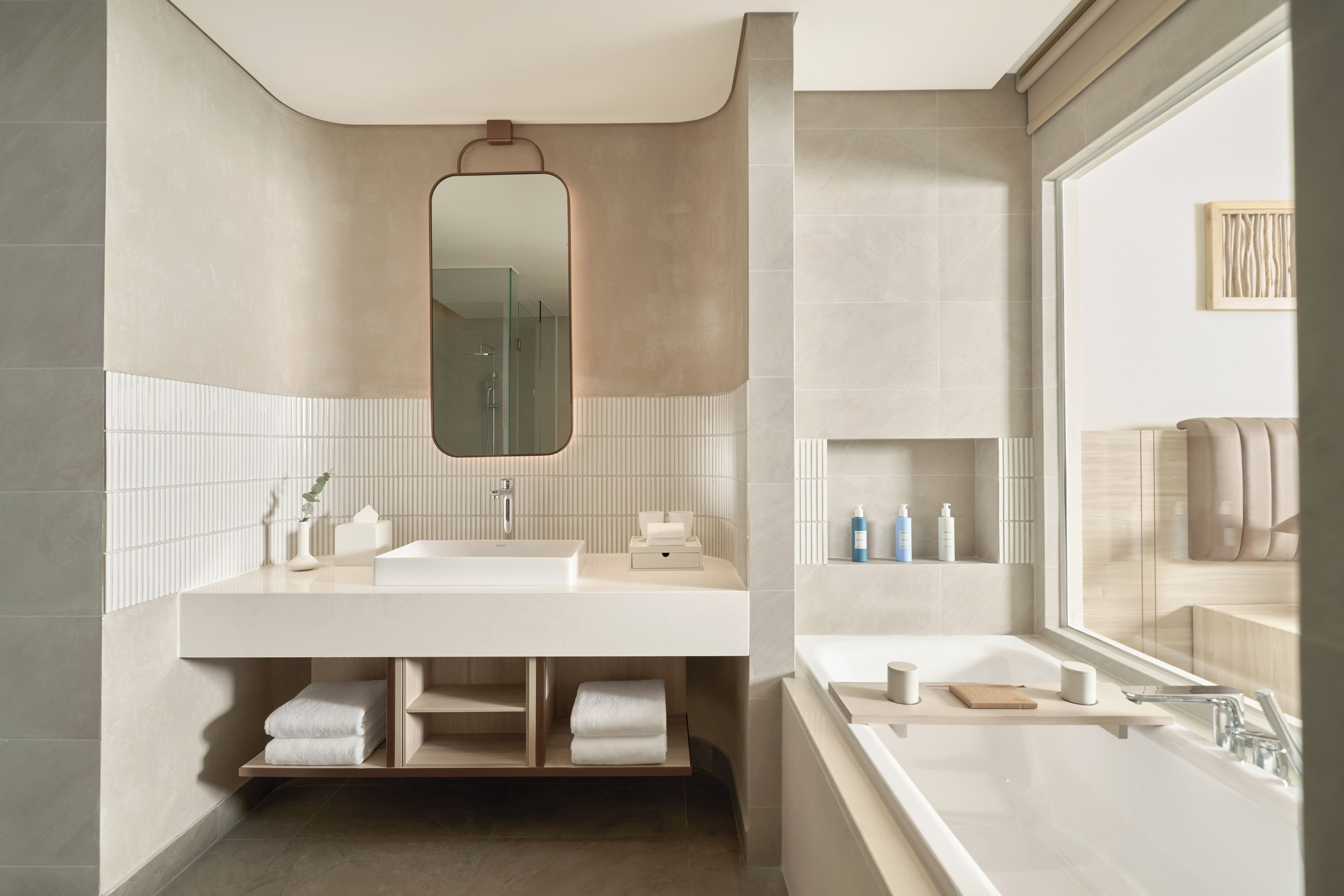 A modern bathroom with a large mirror, a double sink, and a bathtub.