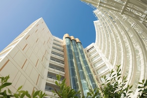 A modern building with a curved glass facade and multiple balconies. - Melia Serenity Cam Ranh Beach Resort (Cam Lam)