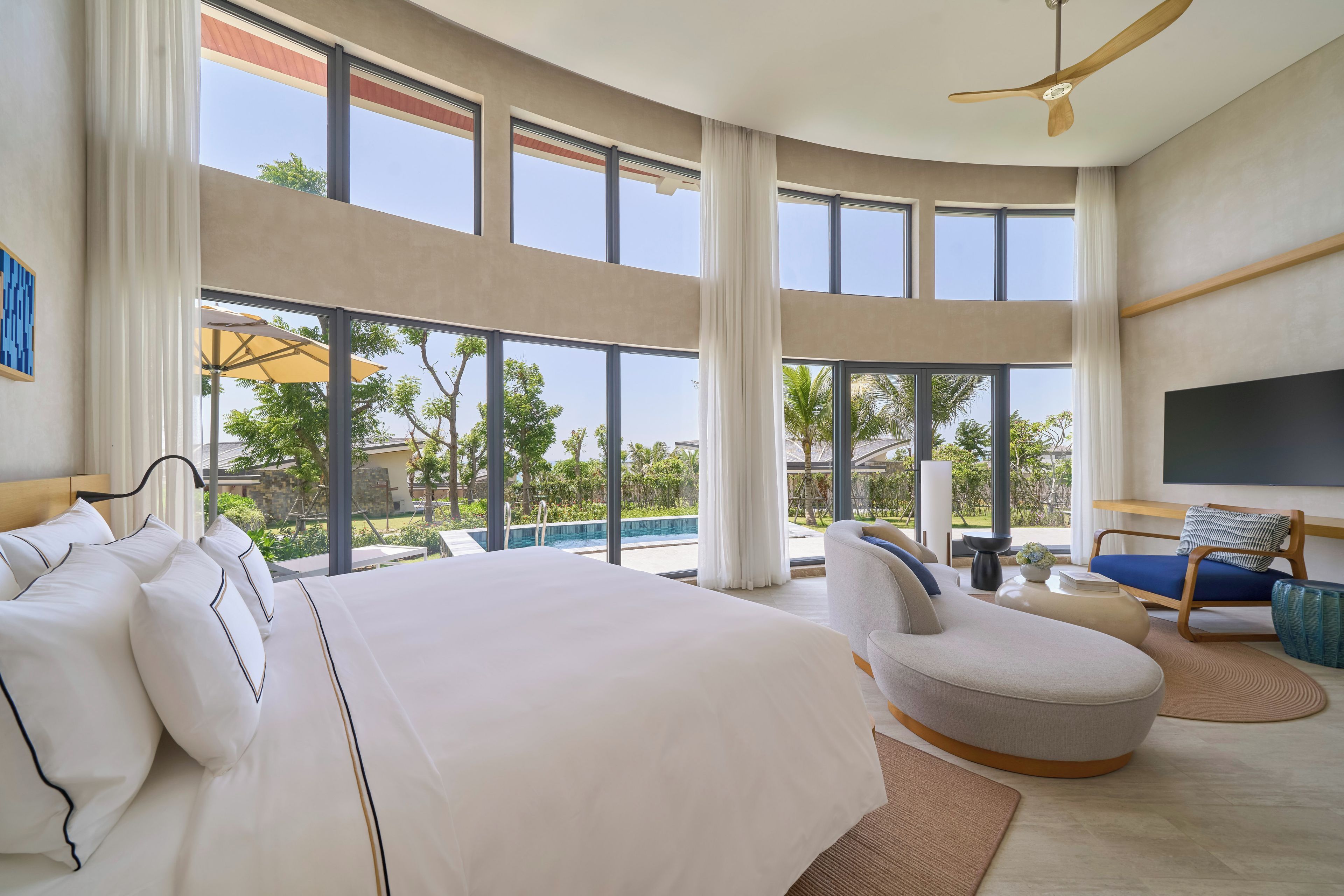 Une chambre d’hôtel moderne dotée d’un grand lit, d’un coin salon et offrant une vue sur l’extérieur.