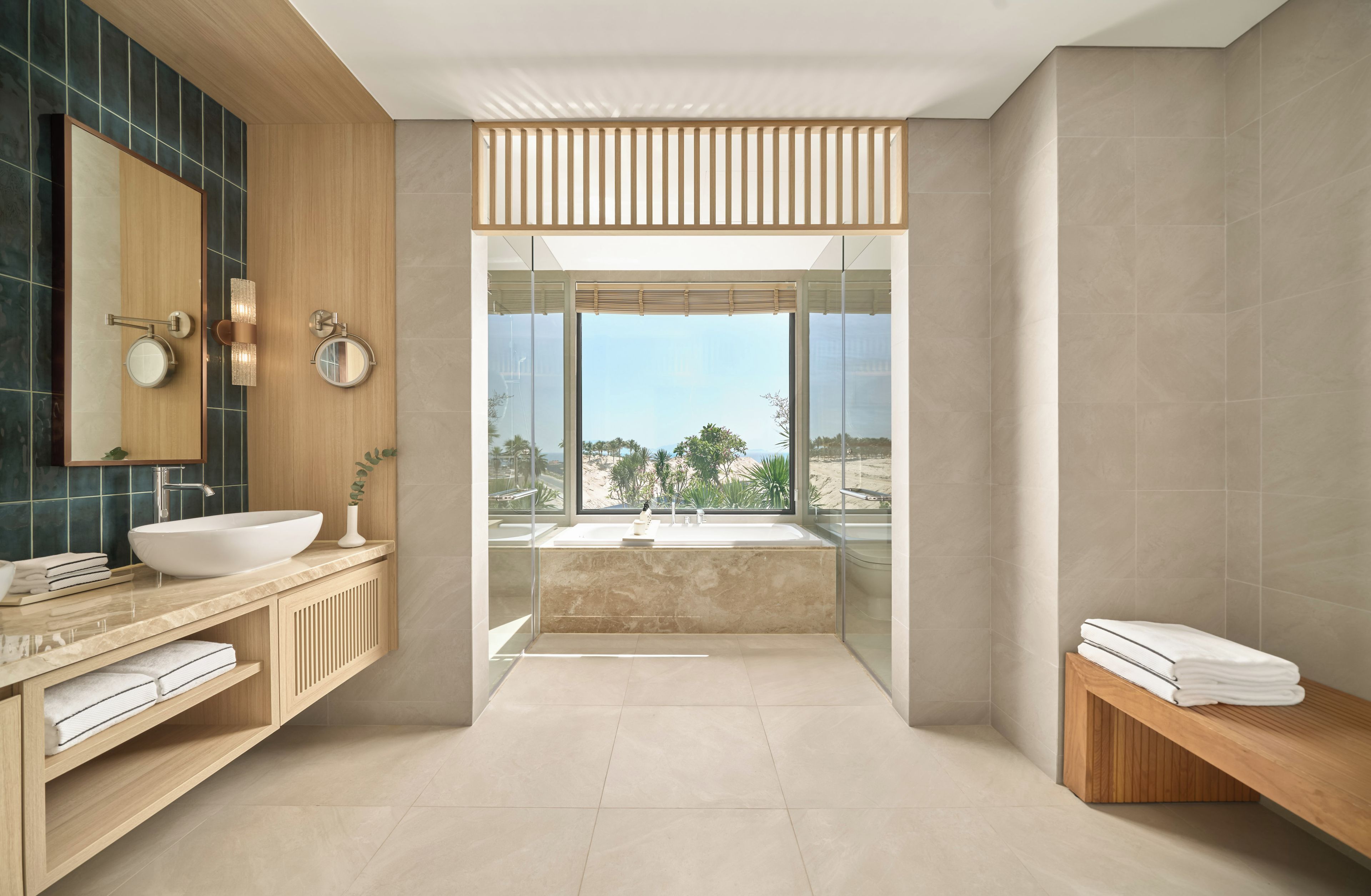 Ein modernes Badezimmer mit einem großen Spiegel, zwei Waschbecken, einer Badewanne und Blick ins Freie.