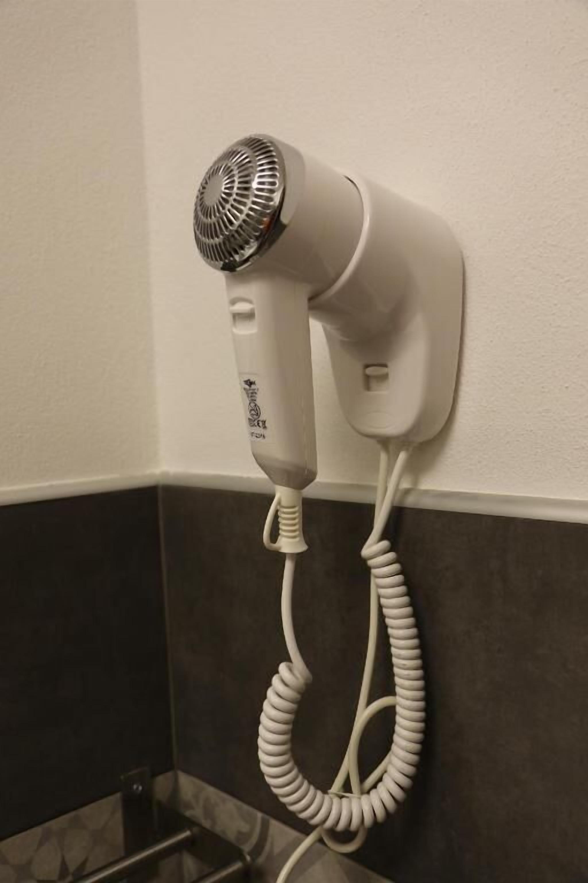 A hair dryer mounted on a wall in a bathroom.