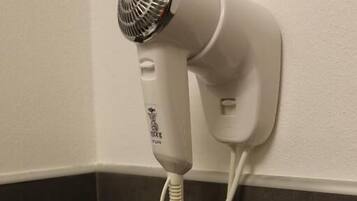 A hair dryer mounted on a wall in a bathroom.