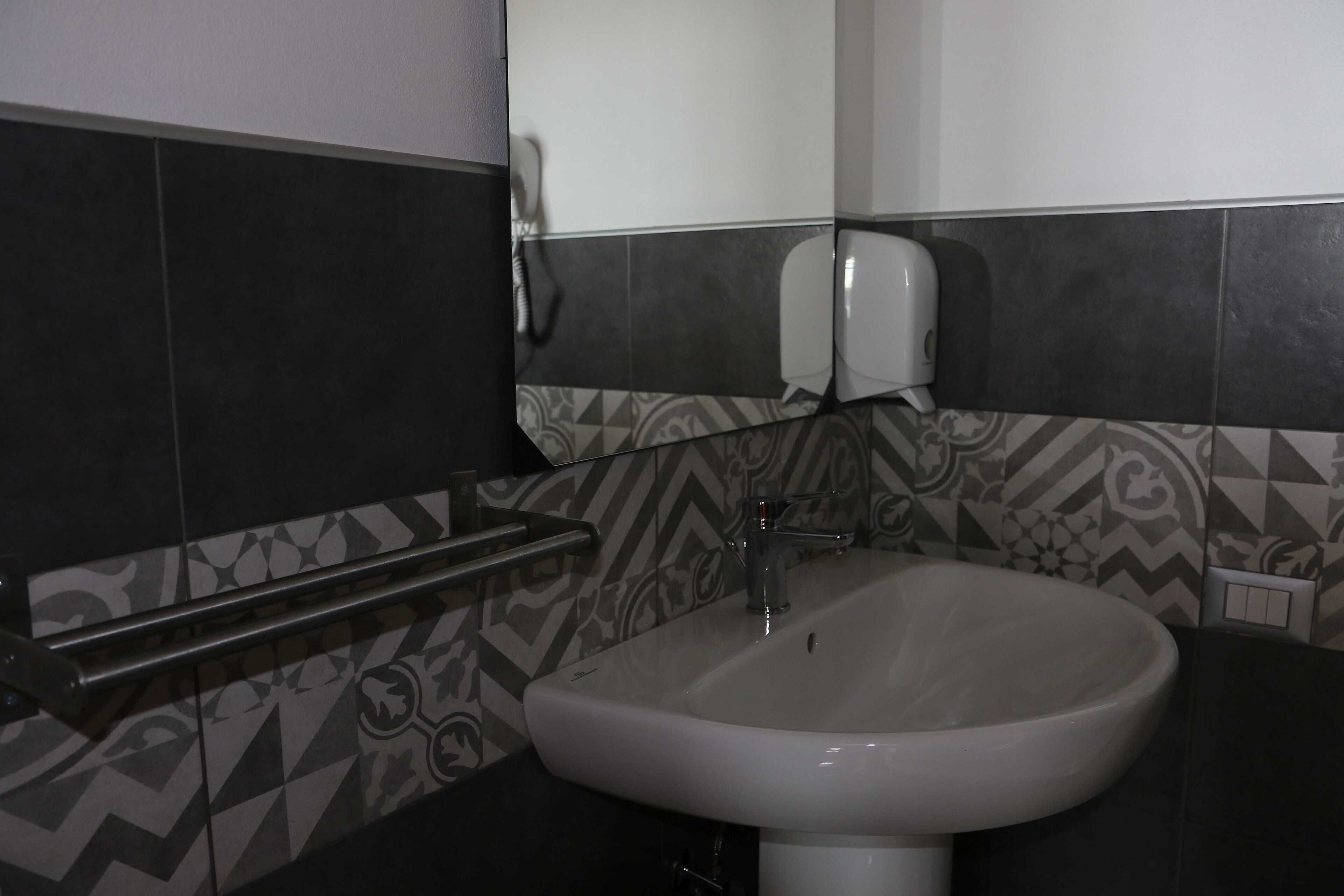A bathroom with a white sink, a towel rack, and patterned tiles.