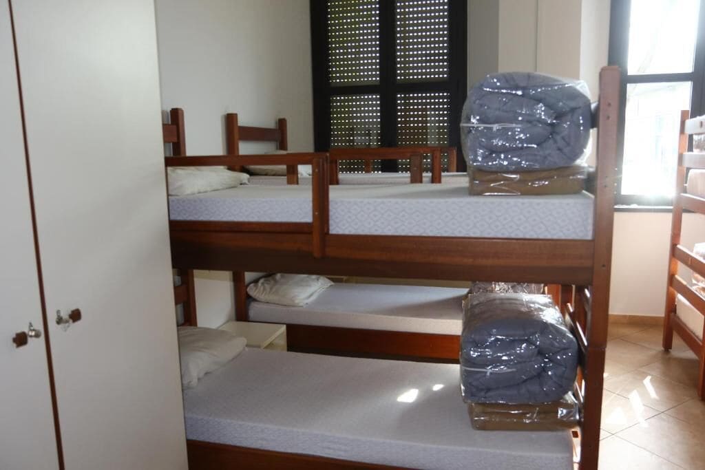 Una habitación con tres literas, un armario y una ventana con persianas.