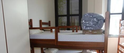 Una habitación con tres literas, un armario y una ventana con persianas.