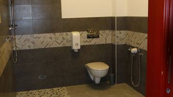 A bathroom with a shower, toilet, and hand dryer.