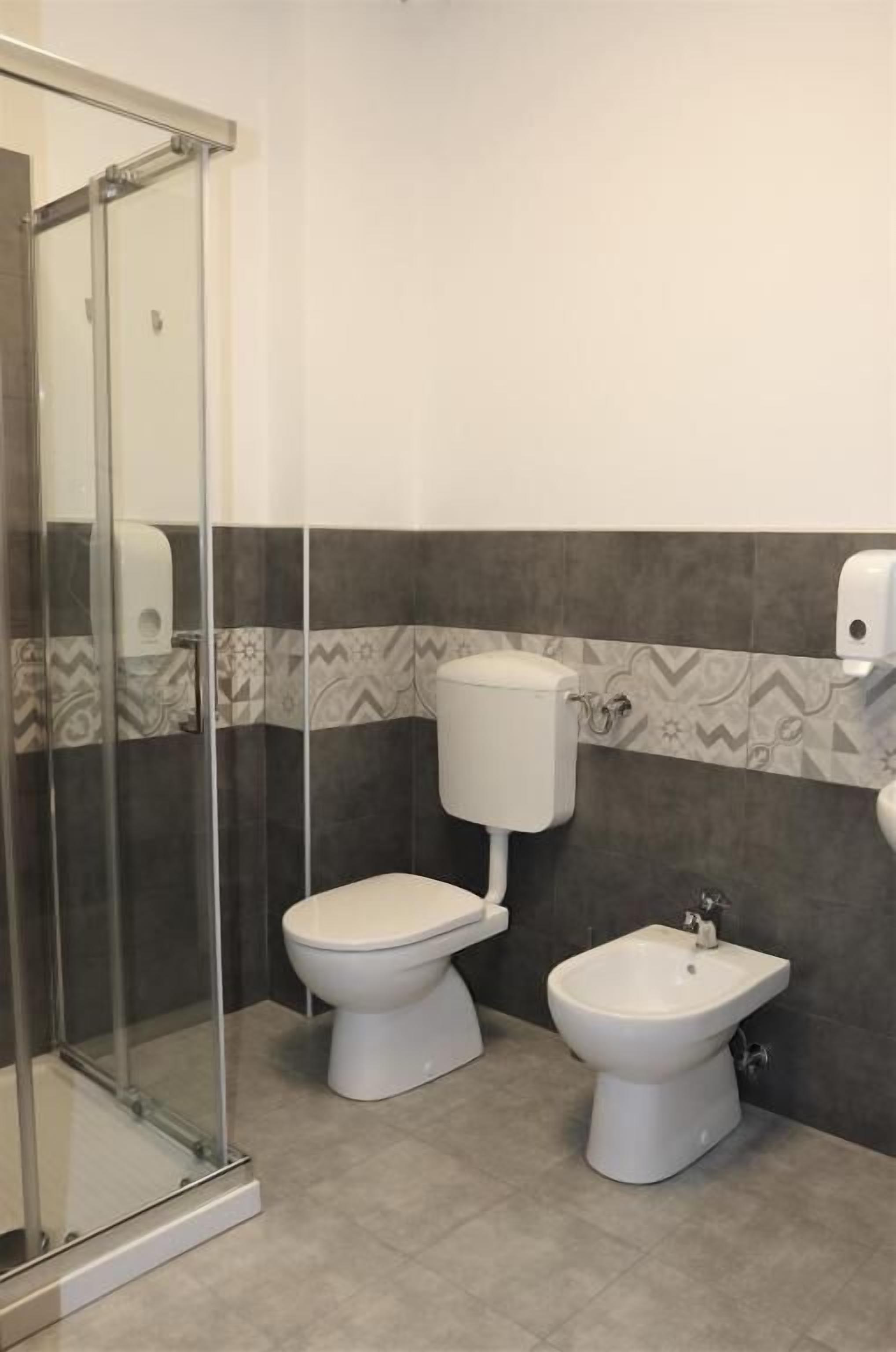 A bathroom with a glass shower enclosure, a toilet, and a bidet.