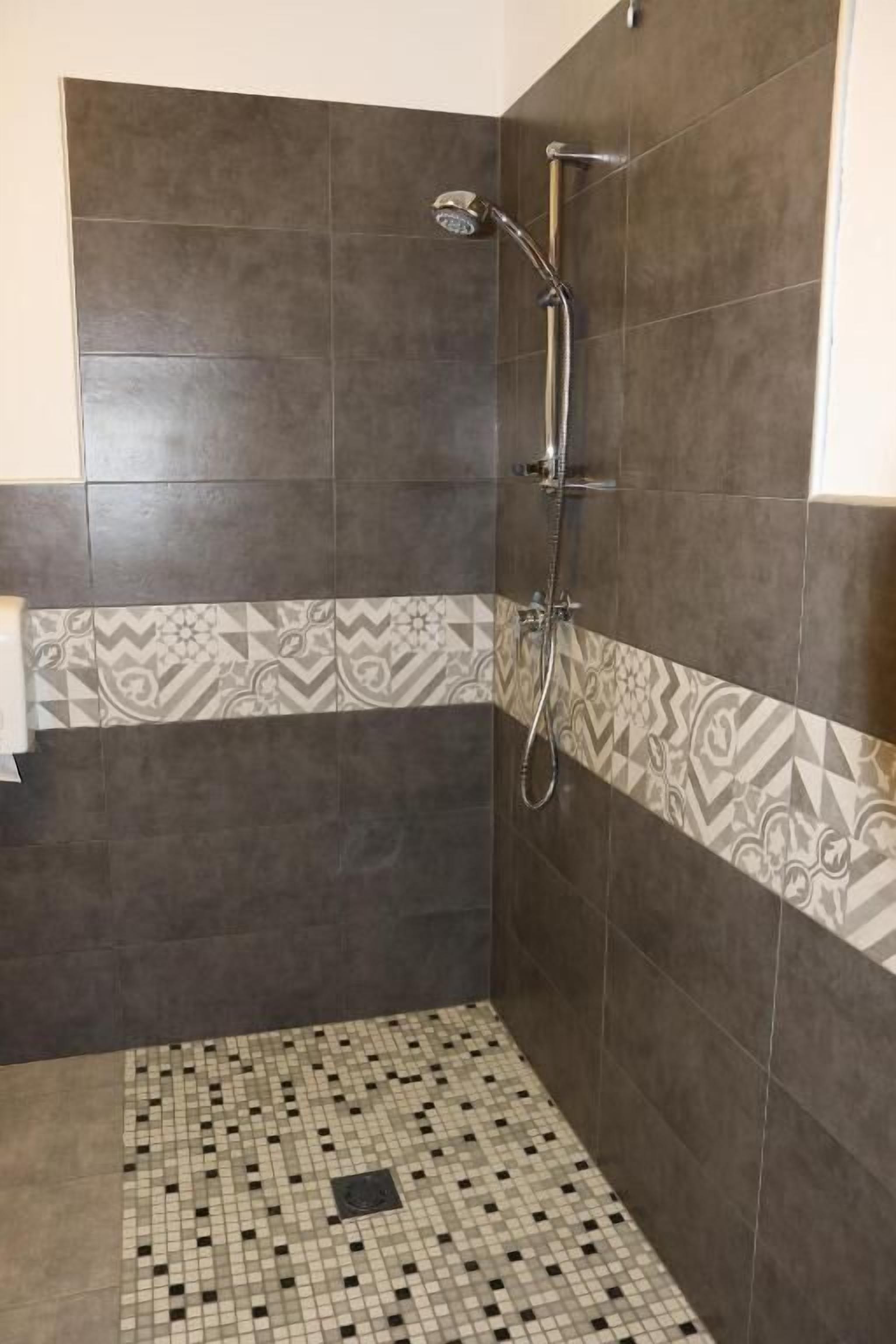 Un espacio para ducha con suelo de baldosas y cabezal de ducha.