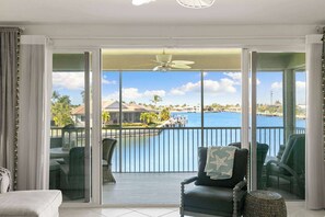 Ein Balkon mit Blick auf einen Yachthafen und Wasser, ausgestattet mit Korbmöbeln und einem Tisch.
