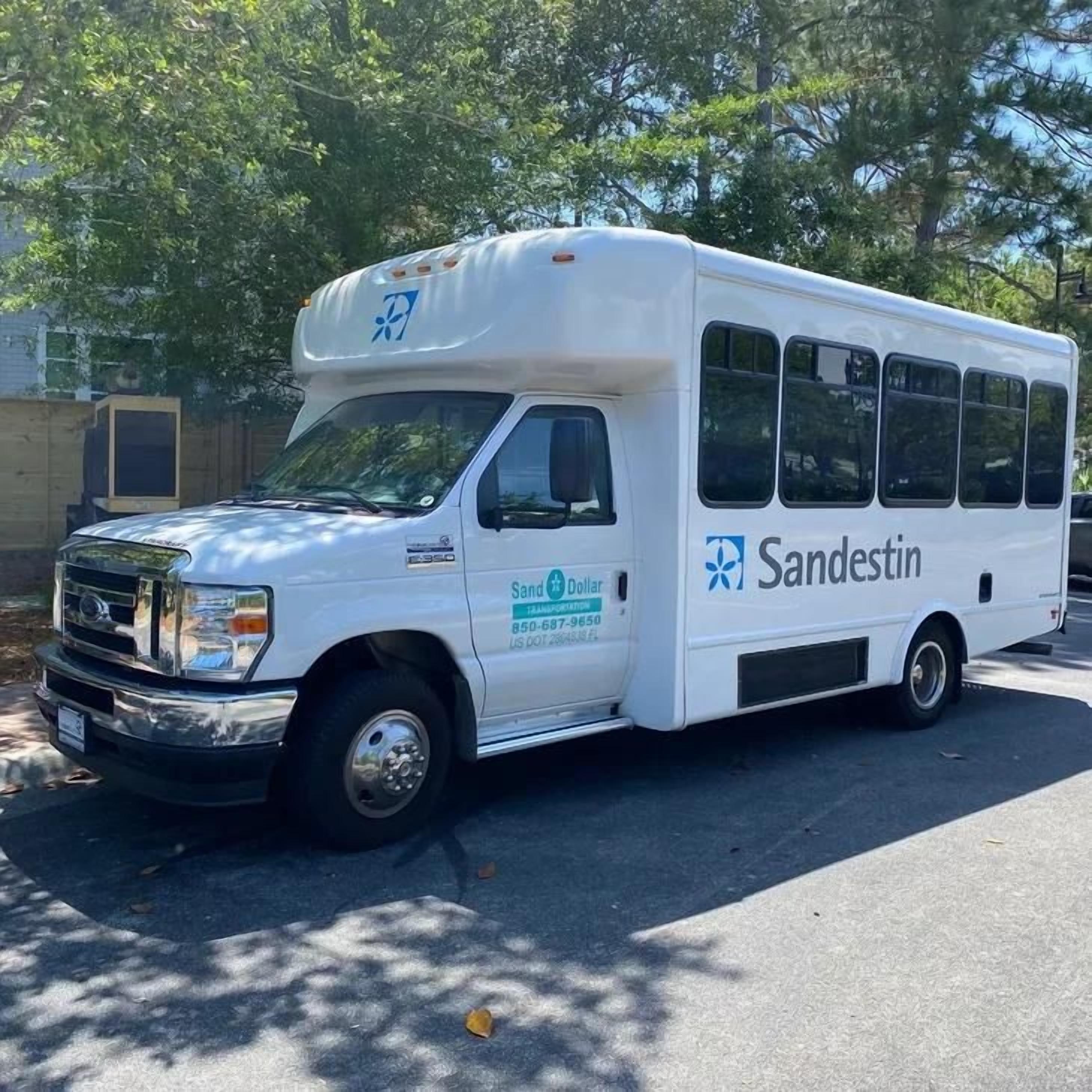 A white Sandestin bus parked on a street.