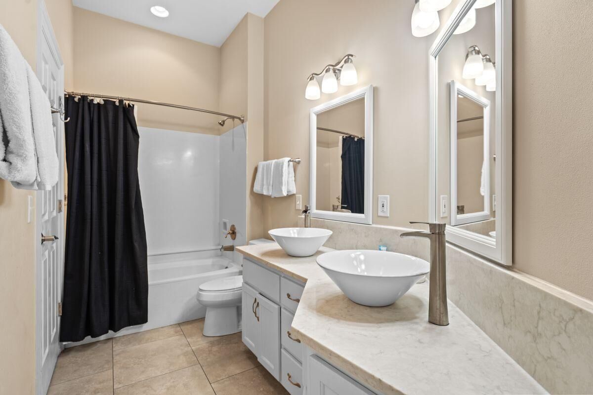 A bathroom with a bathtub, toilet, and two sinks with mirrors.