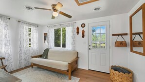 A cozy living room with a wooden sofa, a ceiling fan, and a woven basket. - Cozy 1-bedroom cottage with waterfront views (Townsend)