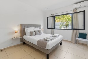 A modern bedroom with a bed, bedside lamps, a window with a view, and a chair.