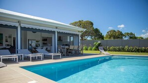 Ein modernes Haus mit Swimmingpool, Sitzgelegenheiten im Freien und einer überdachten Terrasse.