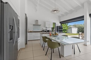 A modern kitchen with a central island, white cabinetry, and a view of the outdoors.