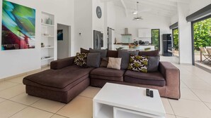 Ein modernes Wohnzimmer mit einem Ecksofa, einem weißen Couchtisch und einer Küche im Hintergrund.