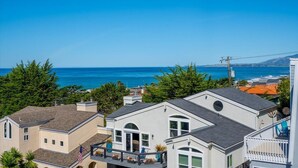 Et kystnært boligområde med huse, en klar blå himmel og havet i baggrunden.