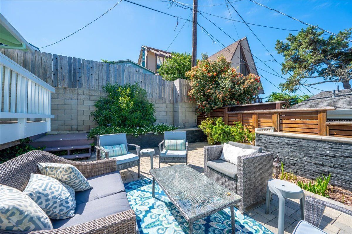 A patio with wicker furniture, a stone wall, and a wooden fence.