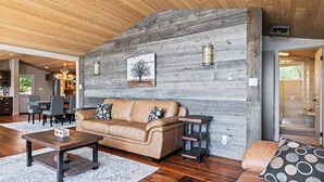 Un soggiorno moderno con soffitto in legno, un divano in pelle, un tavolino da caffè e un camino.