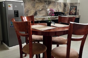 A dining area with a round wooden table, four chairs, a refrigerator, a marble backsplash, and a sink. - Entire accommodation: rental unit in Cusco, Peru (Cusco)