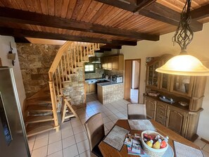 Eine geräumige Küche mit einer Holztreppe, einem Essbereich mit Tisch für zwei Personen und einer großen Chandelier.