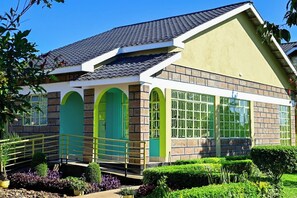 A two-story building with a brick facade, green arched windows, and a tiled roof.