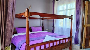 Un letto a baldacchino con struttura in legno e biancheria viola.
